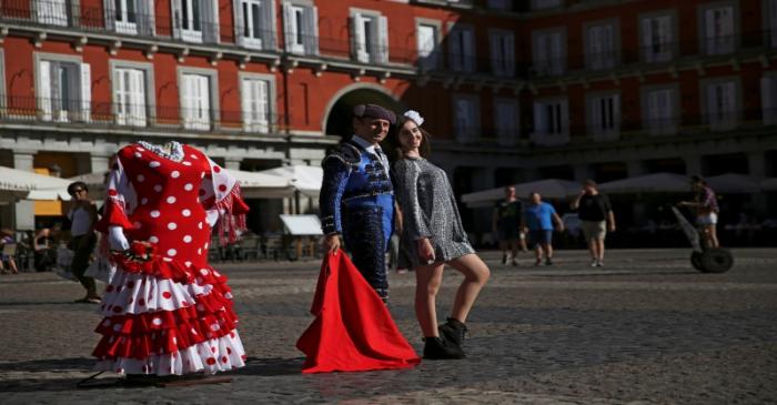 A tourist has her photo taken with a street performer dressed as a bullfighter at Plaza Mayor
