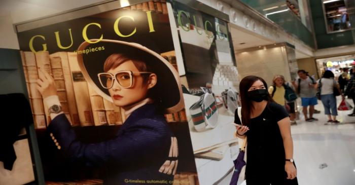 FILE PHOTO: A woman walks past a Gucci advertising poster as shoppers and anti-government