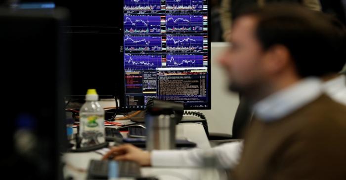 Financial traders work at their desks at CMC Markets in the City of London