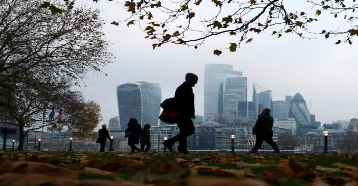 FILE PHOTO: People walk through autumnal leaves in front of the financial district in London