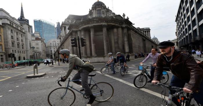 FILE PHOTO: Commuters cycle past the Bank of England in the City of London