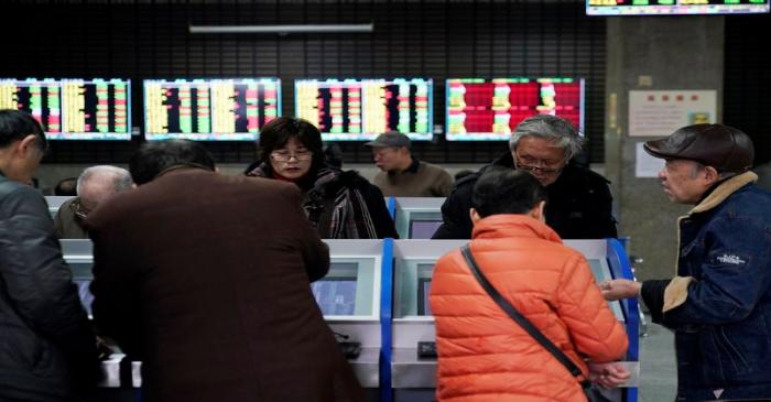 FILE PHOTO: Investors look at computer screens showing stock information at a brokerage house