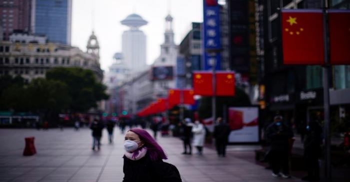 A woman wearing a protective mask stands at the Nanjing Road, in Shanghai