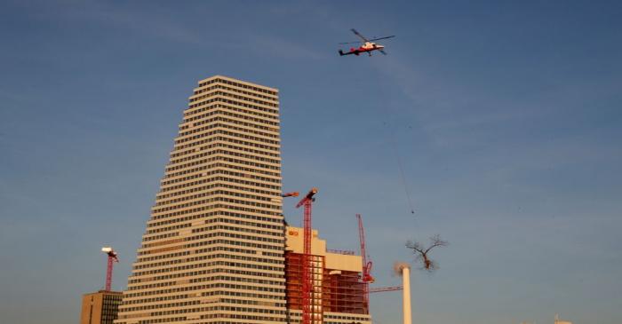 Kaman K-Max K-1200 helicopter transports a tree top in front of headquarters of Swiss drugmaker
