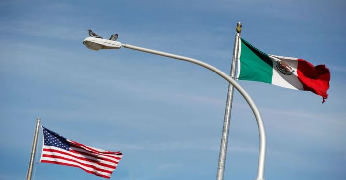 FILE PHOTO: The US flag and the Mexico's flag are pictured on the international border bridge