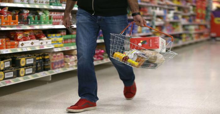 A shopper carries a basket in a supermarket in London