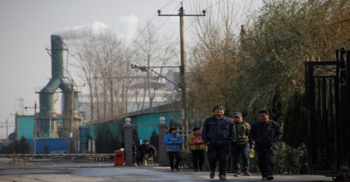 FILE PHOTO: Smoke billows from a chimney as workers leave a factory in rural Gaoyi county near