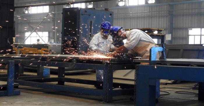 Workers weld shipping container components at a container manufacturing company in Lianyungang