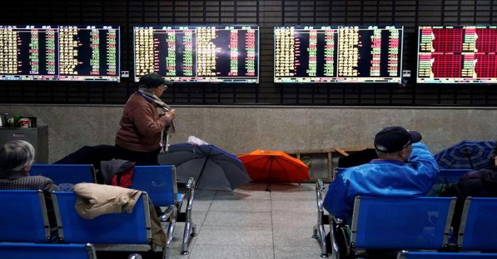 FILE PHOTO: Investors look at screens showing stock information at a brokerage house in