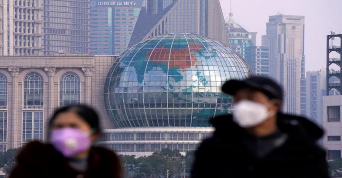 People wearing protective masks are pictured at The Bund in front of the Lujiazui financial