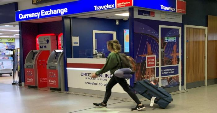 FILE PHOTO: A passenger walks past a Travelex currency exchange at Manchester Airport in