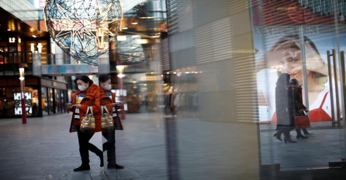 People wearing face masks walk at a shopping mall, as the country is hit by an outbreak of the