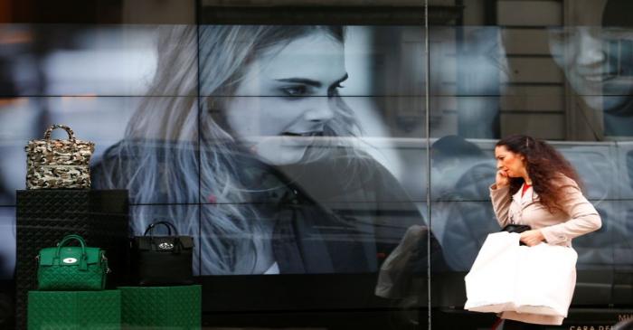 FILE PHOTO: A woman walks past a video display in the shop window of a Mulberry store in