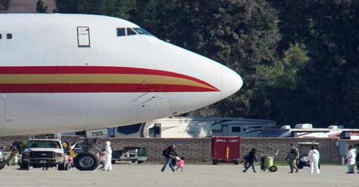 FILE PHOTO: Women and children walks past personnel in protective clothing after arriving on an