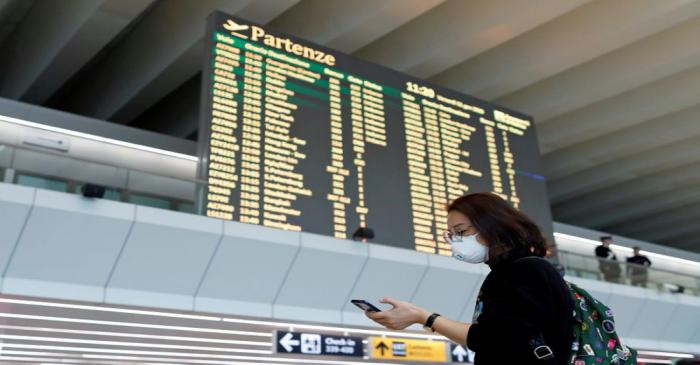 Passenger in a protective mask uses her phone on at Rome's Fiumicino airport