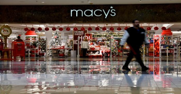 Shoppers walk past a Macy's storefront display as holiday shopping accelerates at the King of