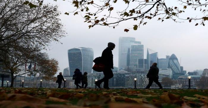FILE PHOTO: People walk through autumnal leaves in front of the financial district in London