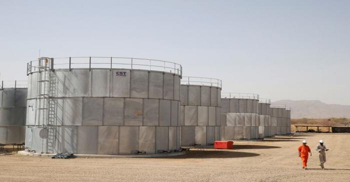 FILE PHOTO: Workers walk past storage tanks at Tullow Oil's Ngamia 8 drilling site in Lokichar