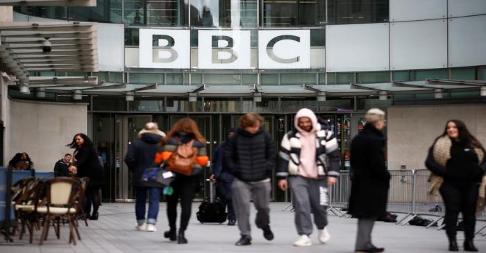 Pedestrians walk past a BBC logo at Broadcasting House, as the corporation announced it will
