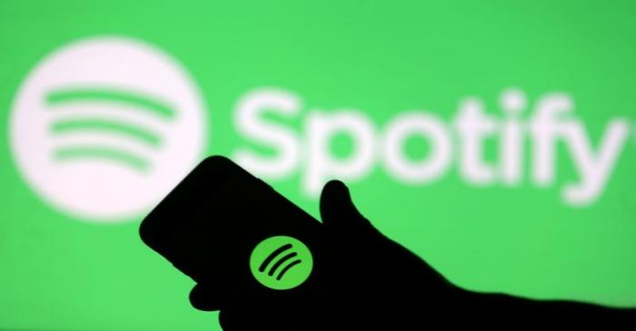FILE PHOTO: A smartphone is seen in front of a screen projection of Spotify logo, in this