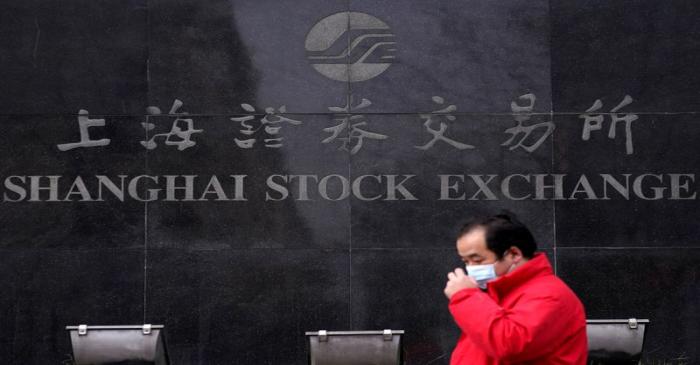 FILE PHOTO: A man wearing a mask walk at the Shanghai Stock Exchange building at the Pudong