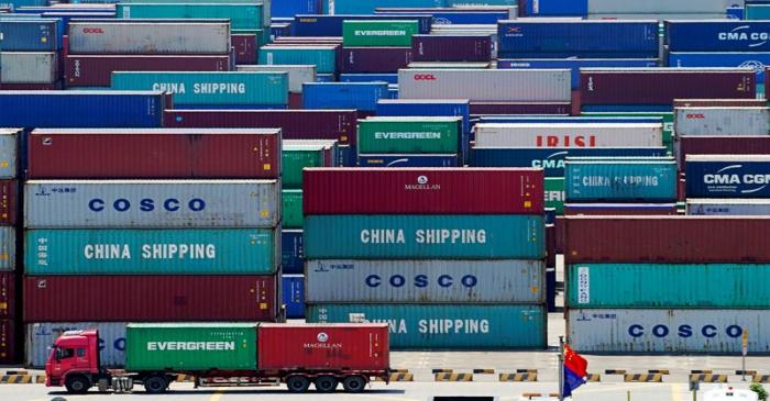 FILE PHOTO: Truck carrying containers are seen near a Chinese flag at the Yangshan Deep Water