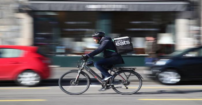 An Uber Eats food delivery courier rides an electric bike in Geneva