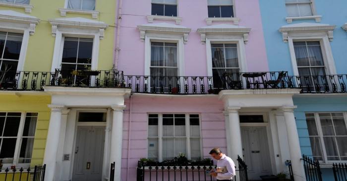 FILE PHOTO:  A man walks past houses painted in various colours in a residential street in