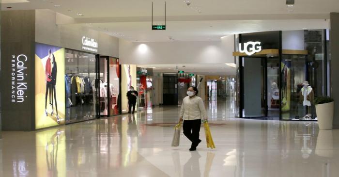 FILE PHOTO: Cleaner wearing a mask walks at a shopping mall in Beijing's central business area