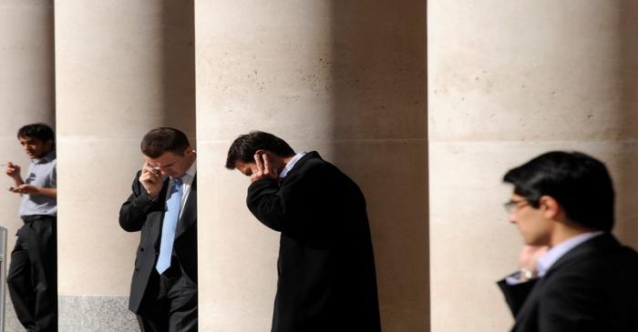 City workers make phone calls outside the London Stock Exchange in Paternoster Square in the