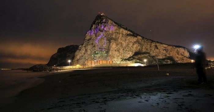 FILE PHOTO: A Spanish fisherman stands on a beach while an outline of the Queen Elizabeth II is