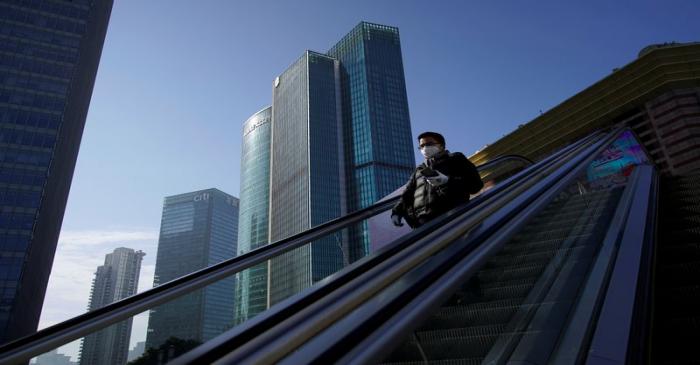 A man wearing a face mask rides an escalator at the Lujiazui financial district in the morning