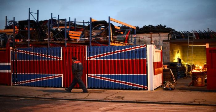 A man walks past a car scrap yard in east London