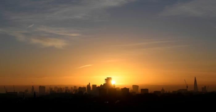 FILE PHOTO: The sun is seen rising behind skyscrapers and buildings in in the City of London