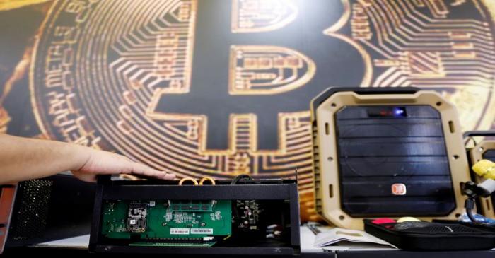 A cryptocurrency mining computer is seen in front of bitcoin logo during the annual Computex