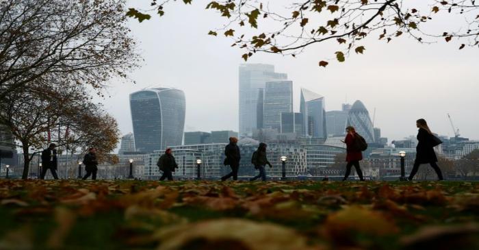 FILE PHOTO: People walk through autumnal leaves in front of the financial district in London