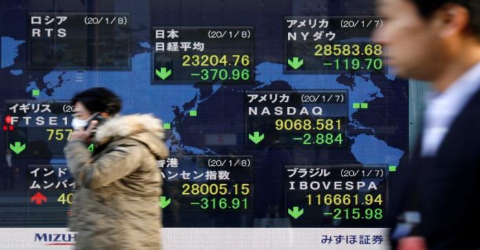 People walk past an electronic display showing world markets indices outside a brokerage in