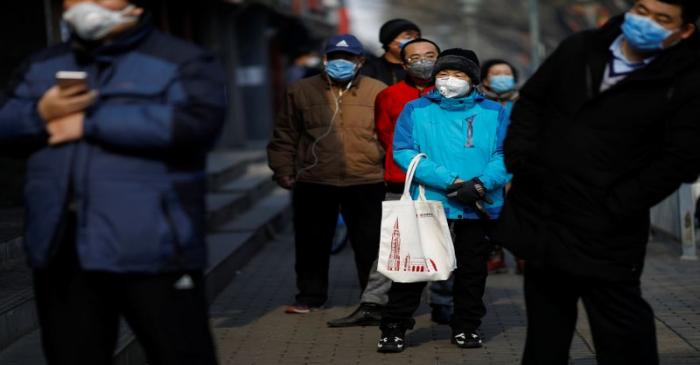 Customers wearing face masks queue for food outside a store, as the country is hit by an