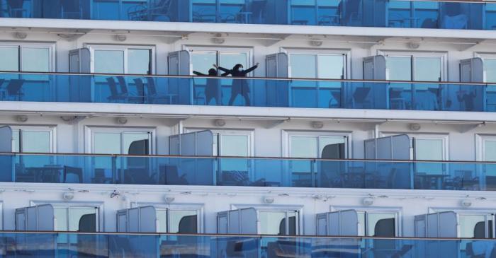 FILE PHOTO: A passenger stretches on the balcony of a cabin of the cruise ship Diamond