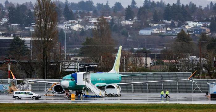 Employees walk near a Boeing 737 Max aircraft at the Renton Municipal Airport in Renton