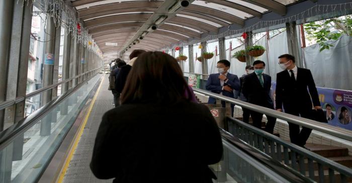 FILE PHOTO: People wear protective masks as they walk through the financial central district,