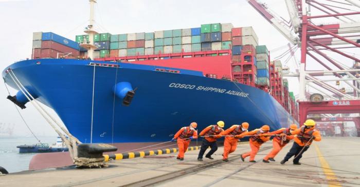 Workers wearing face masks rope a container ship at a port in Qingdao