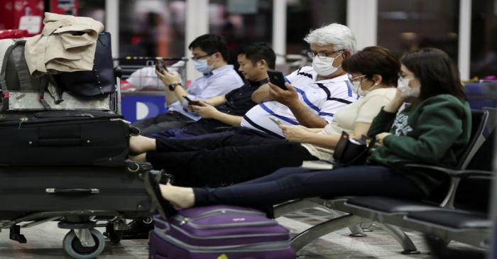 Travellers, wearing masks as a precautionary measure to avoid contracting coronavirus, are seen
