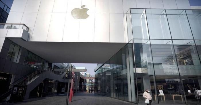 Man wearing a face mask walks past a closed Apple store at Sanlitun in Beijing
