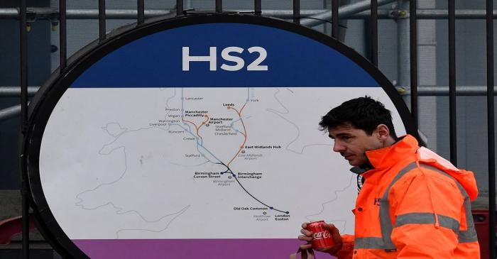 FILE PHOTO: An HS2 worker walks past signage on perimeter fencing at the HS2 high speed rail