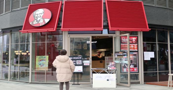 FILE PHOTO: Customer waits to pick up her order outside a KFC restaurant as the country is hit