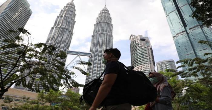 FILE PHOTO: Tourists wearing masks pass by Petronas Twin Towers in Kuala Lumpur