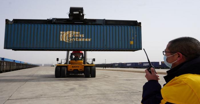 Workers transport a container from a China-Europe freight train that departed from Russia's