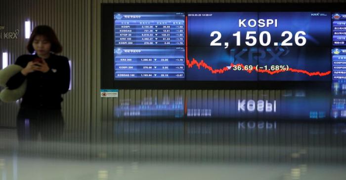 A woman walks past an electronic board showing the KOSPI at the Korea Exchange in Seoul