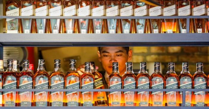 FILE PHOTO: A bartender takes a bottle of Johnnie Walker whisky at Barmaglot bar in Almaty